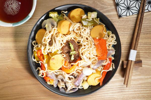 Wok de nouilles Mie et saucisse végane asiatique  Nous cuisinons ici une poêlée de nouilles colorée avec beaucoup de légumes, une marinade épicée faite maison et la délicieuse saucisse à rôtir vegan, style asiatique. Un plat qui comble et rassasie.